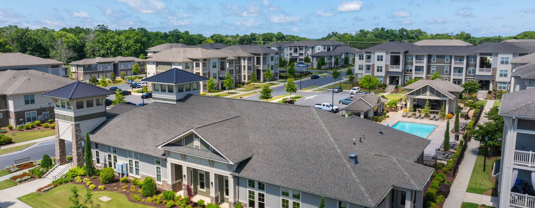 Aerial view featuring a large clubhouse, resort-style pool, and landscaped grounds.