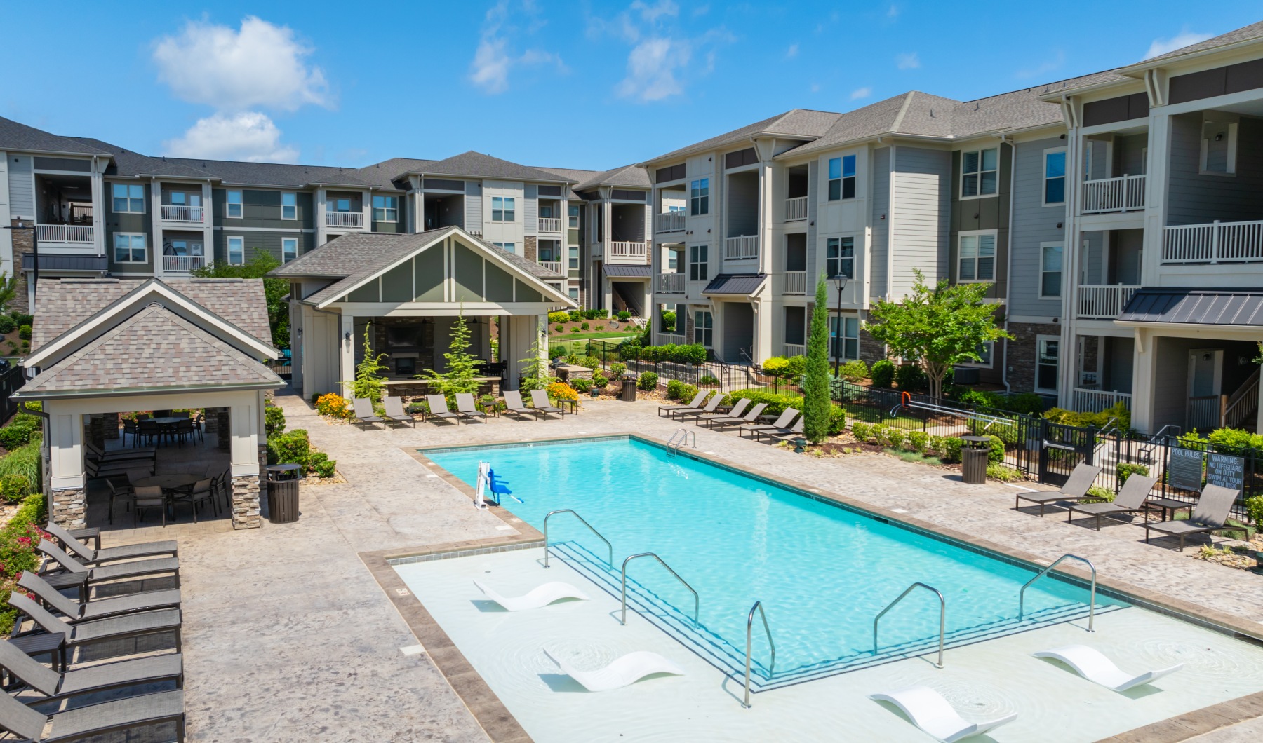 Resort-style swimming pool surrounded by lounge chairs and landscaped courtyard at a modern apartment community
