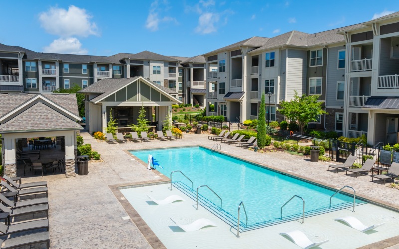 Resort-style swimming pool with in-water lounge chairs, sundeck seating, and covered cabana area