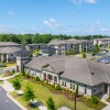 Aerial view of a modern apartment community with landscaped grounds, clubhouse, and multiple residential buildings.