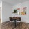 Dining area with round table, chairs, and colorful wall art.